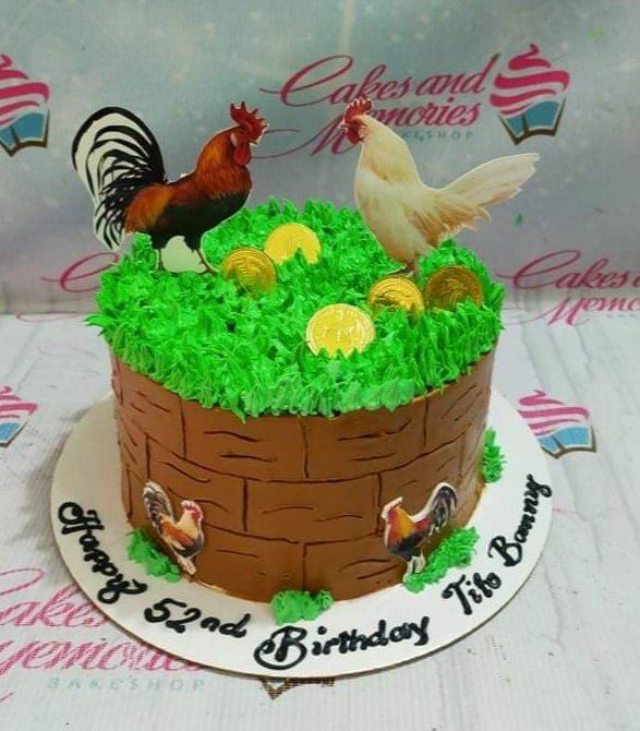 A brown basket-textured cake with green grass icing on top, featuring rooster and hen toppers and gold chocolate coins.