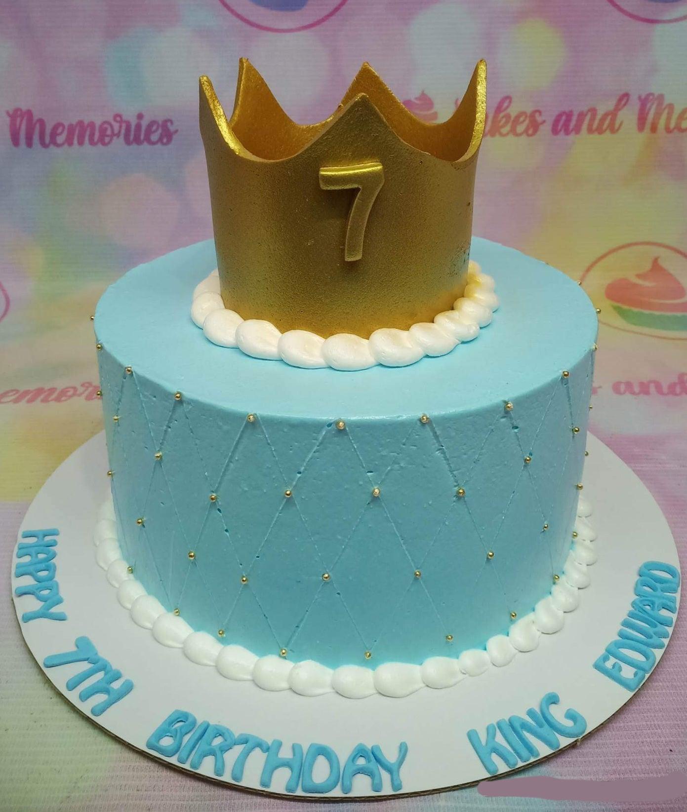 Light blue 1-tier birthday cake with a large gold crown topper, quilted side pattern with gold beads, and white icing borders.