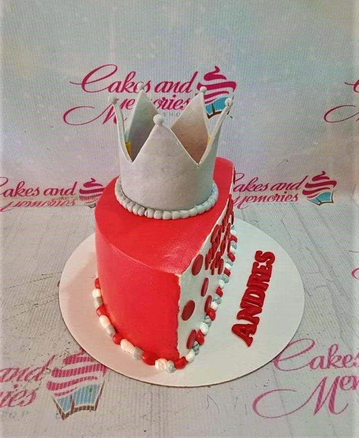 Red and white heart-shaped crown cake with silver toy crown and red gumpaste letters on the base board.