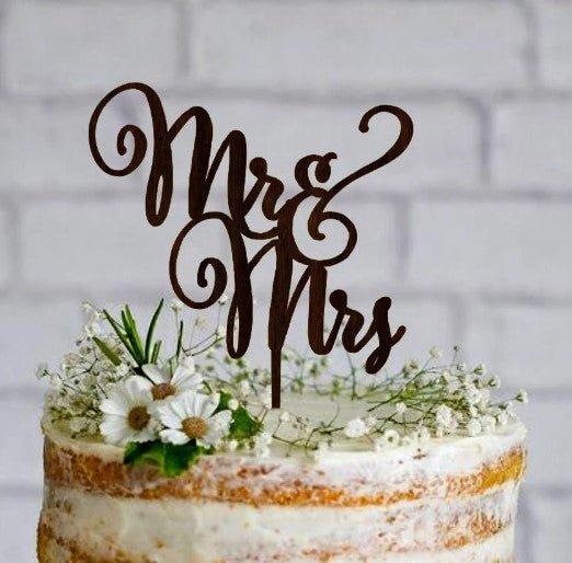 Semi-naked rustic wedding cake with a wooden Mr & Mrs topper and fresh baby's breath and daisy flowers.
