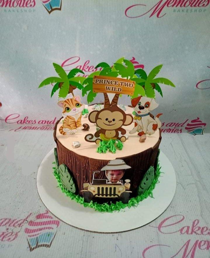 Safari themed tree stump cake with printout toppers of a monkey, cat, dog, and a child in a jeep.