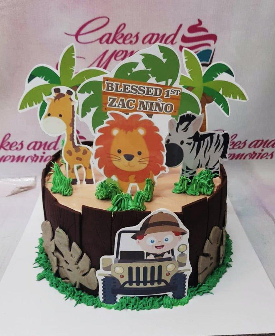 Safari themed birthday cake with brown fence icing, green grass borders, and animal printouts including a lion, giraffe, and zebra.