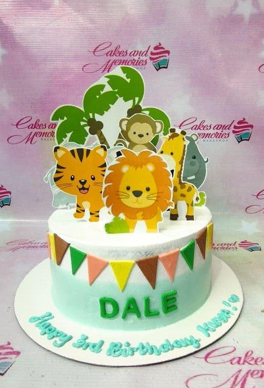 Safari animal themed birthday cake with lion, tiger, giraffe, and monkey toppers on a light blue and white gradient icing base.