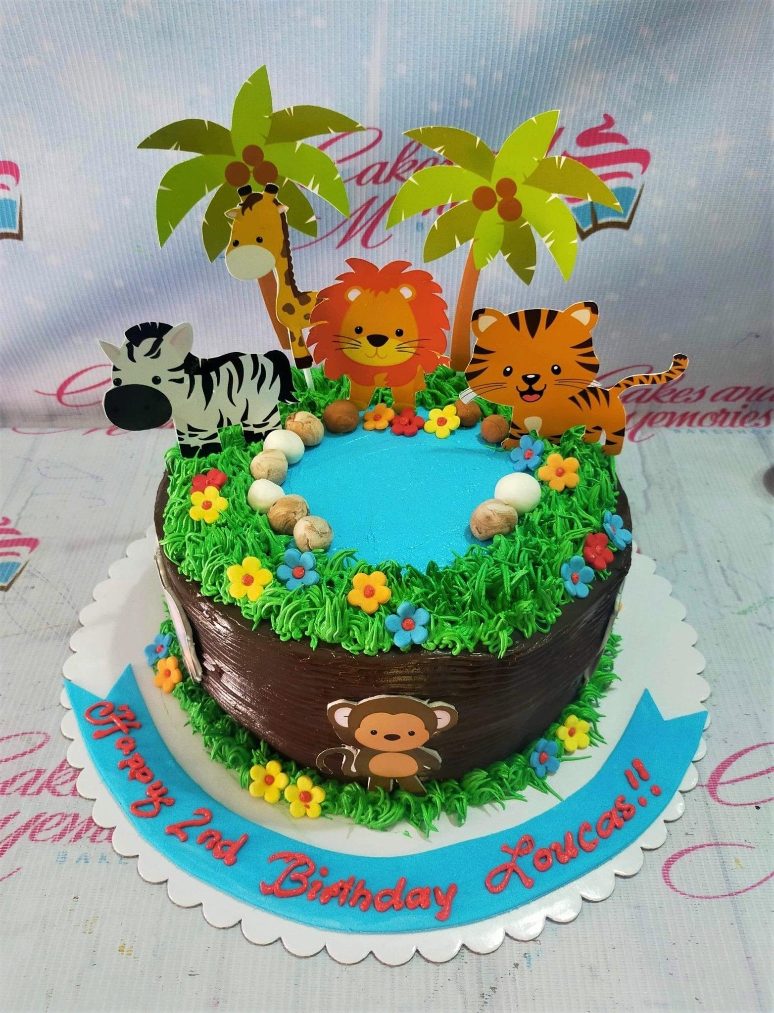 Safari jungle themed birthday cake with chocolate icing, green grass piping, and animal printouts including a lion, tiger, zebra, and giraffe.
