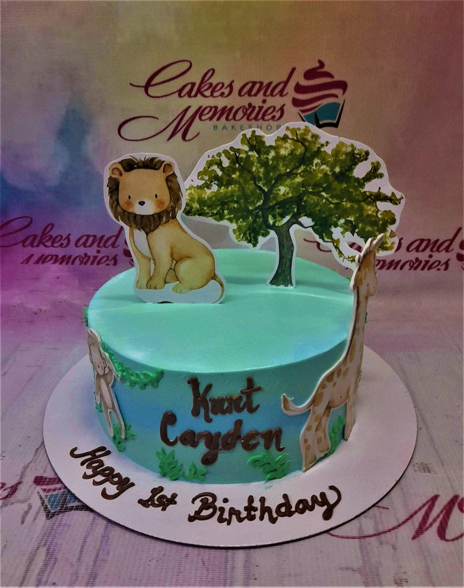 Safari themed birthday cake with a lion, giraffe, and tree printout toppers on light blue icing.