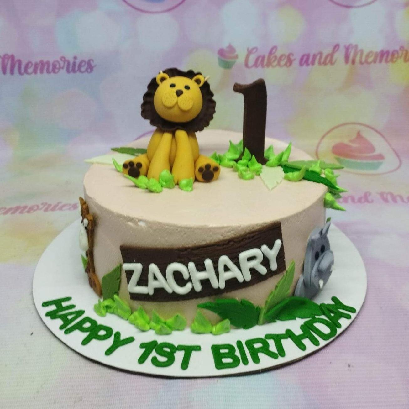 Safari themed 1st birthday cake for Zachary featuring a fondant lion, number 1 topper, and jungle leaves on light brown icing.