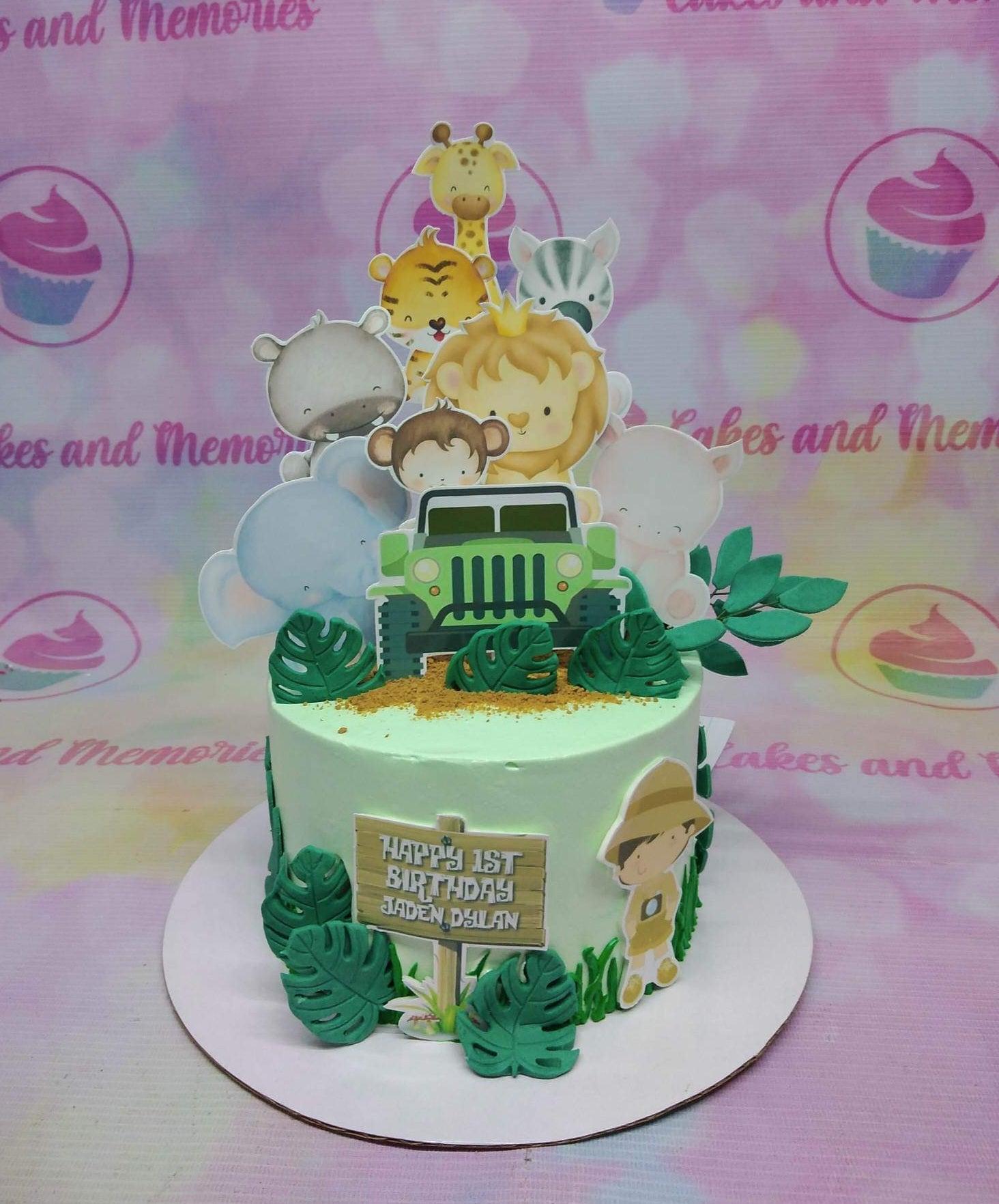 Light green safari themed birthday cake with cute animal printouts, a green jeep, and gumpaste monstera leaves.