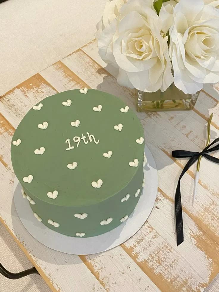 Minimalist sage green cake with white icing hearts and 19th message on top