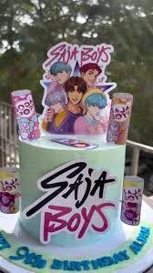 Mint green K-pop themed birthday cake featuring Saja Boys character printouts and soda can decorations.