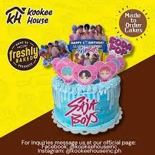 Blue and white striped K-pop themed cake with Saja Boys printouts and pink heart toppers.