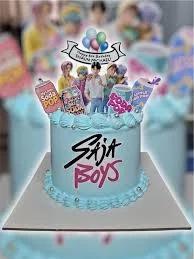 Light blue K-pop themed birthday cake with printed character toppers, soda pop cutouts, and silver dragees.