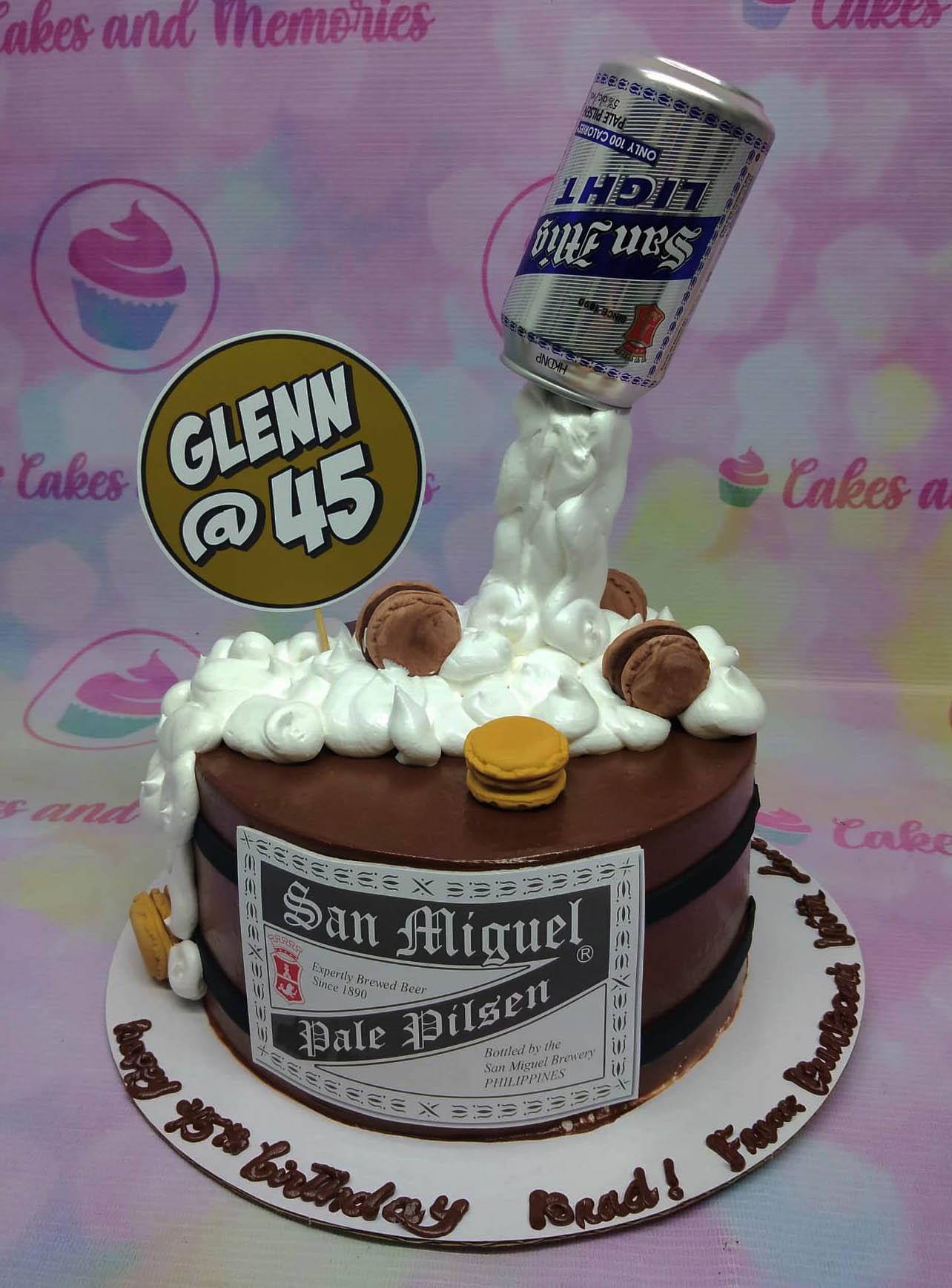 San Miguel Beer themed chocolate cake with a pouring beer can topper and white icing foam.