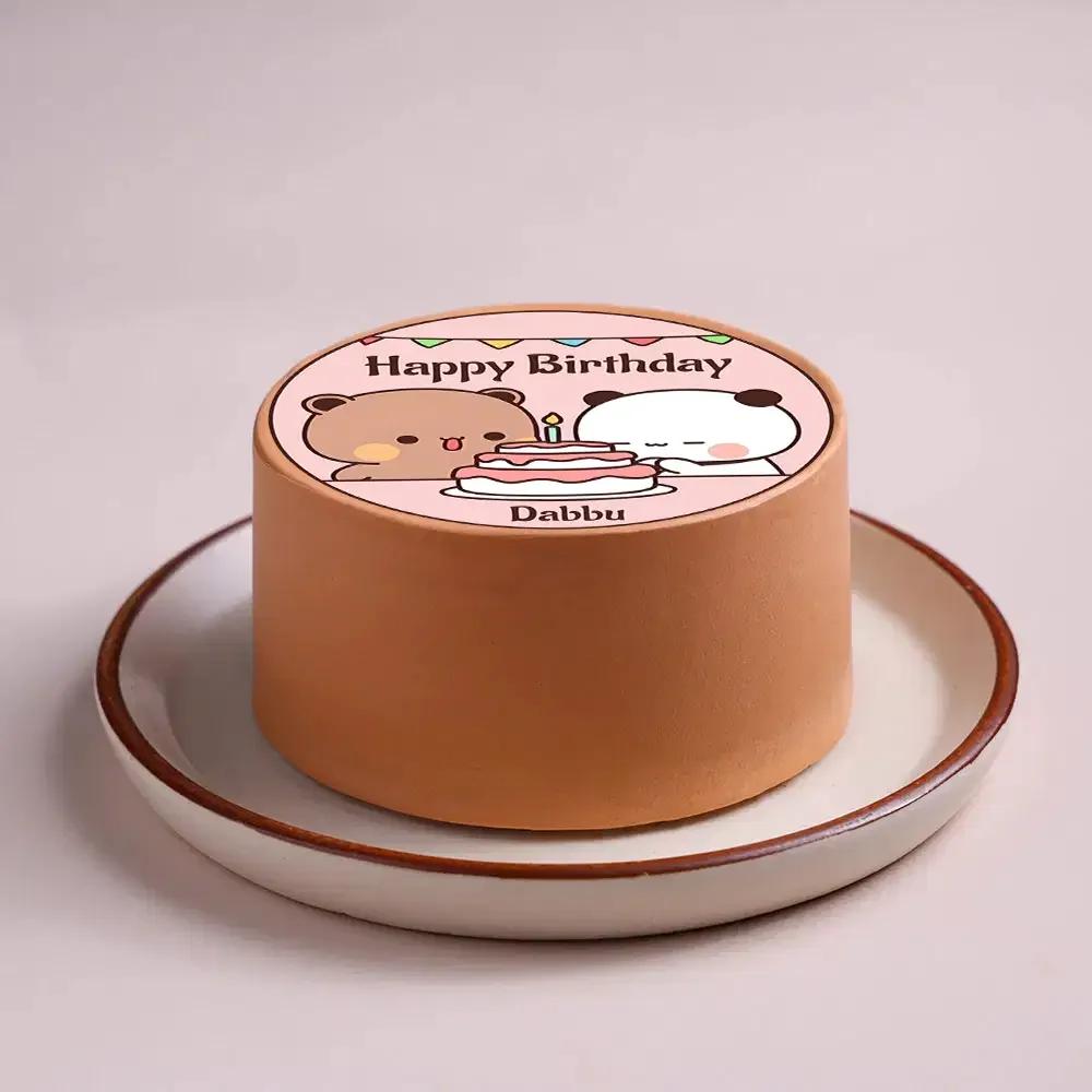 Bento cake with brown icing featuring a printed topper of Sanrio-style bears celebrating with a cake and a Happy Birthday message.