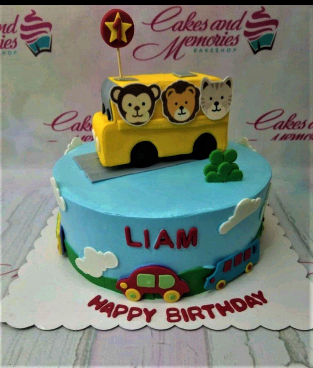 Light blue school bus themed birthday cake for Liam with animal characters and fondant car decorations.
