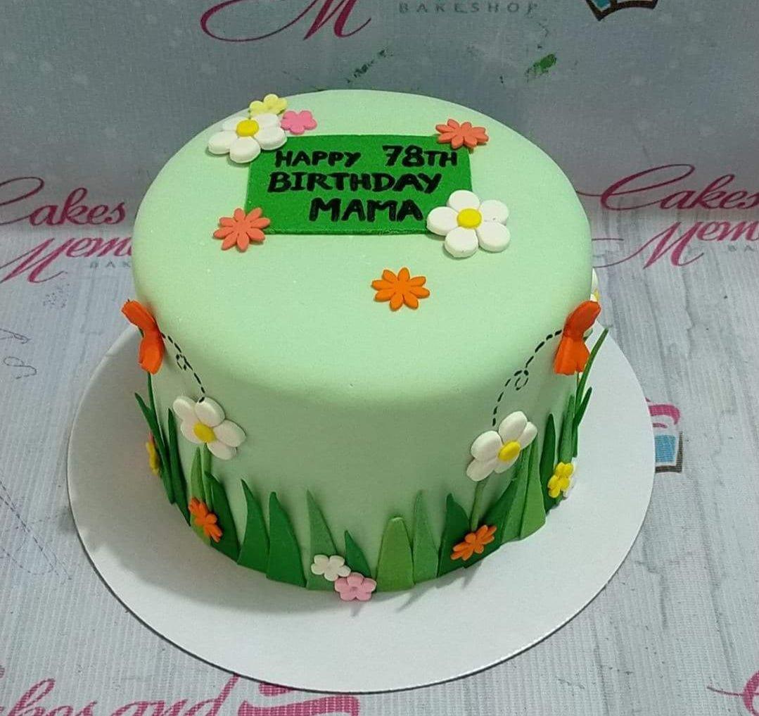 Light green fondant cake for a 78th birthday featuring edible flowers, grass details, and a green message plaque.