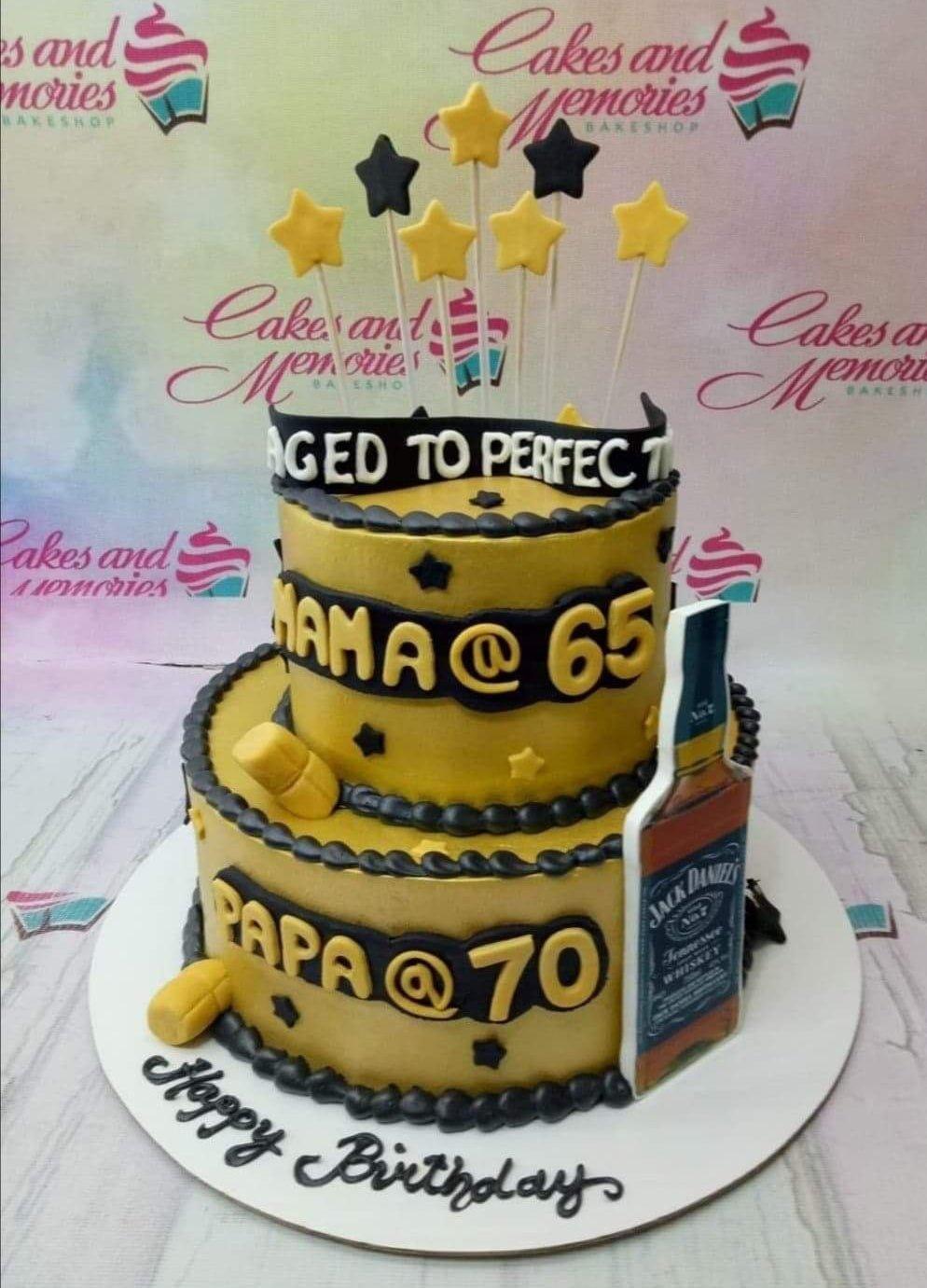 Yellow and black 2-tier birthday cake for a 65th and 70th birthday with stars and a whiskey bottle topper.