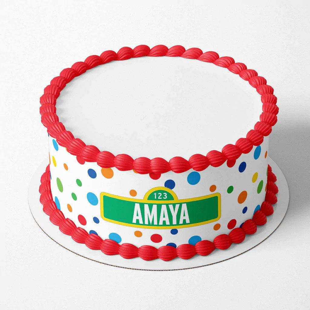 Sesame Street themed birthday cake for Amaya with red icing borders and colorful polka dots on a white base.