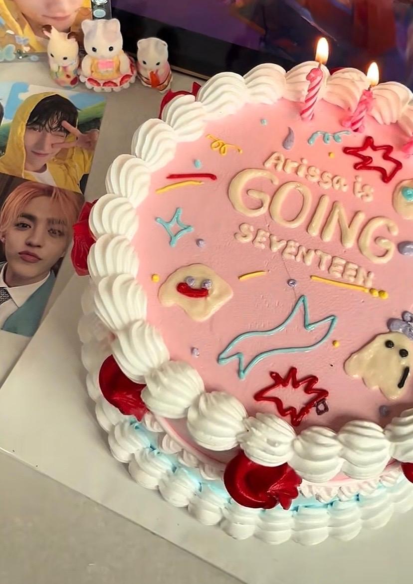 Pink minimalist birthday cake with white icing ruffles, red icing hearts, and a Seventeen K-pop themed message.