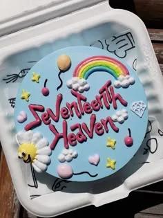 Light blue bento cake with a colorful piped rainbow, clouds, balloons, and a smiley daisy with the message Seventeenth Heaven.