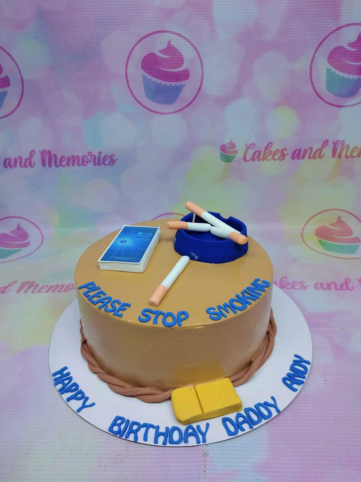 Brown round cake with fondant cigarette pack, ashtray, and cigarettes, featuring a 'Please Stop Smoking' message.