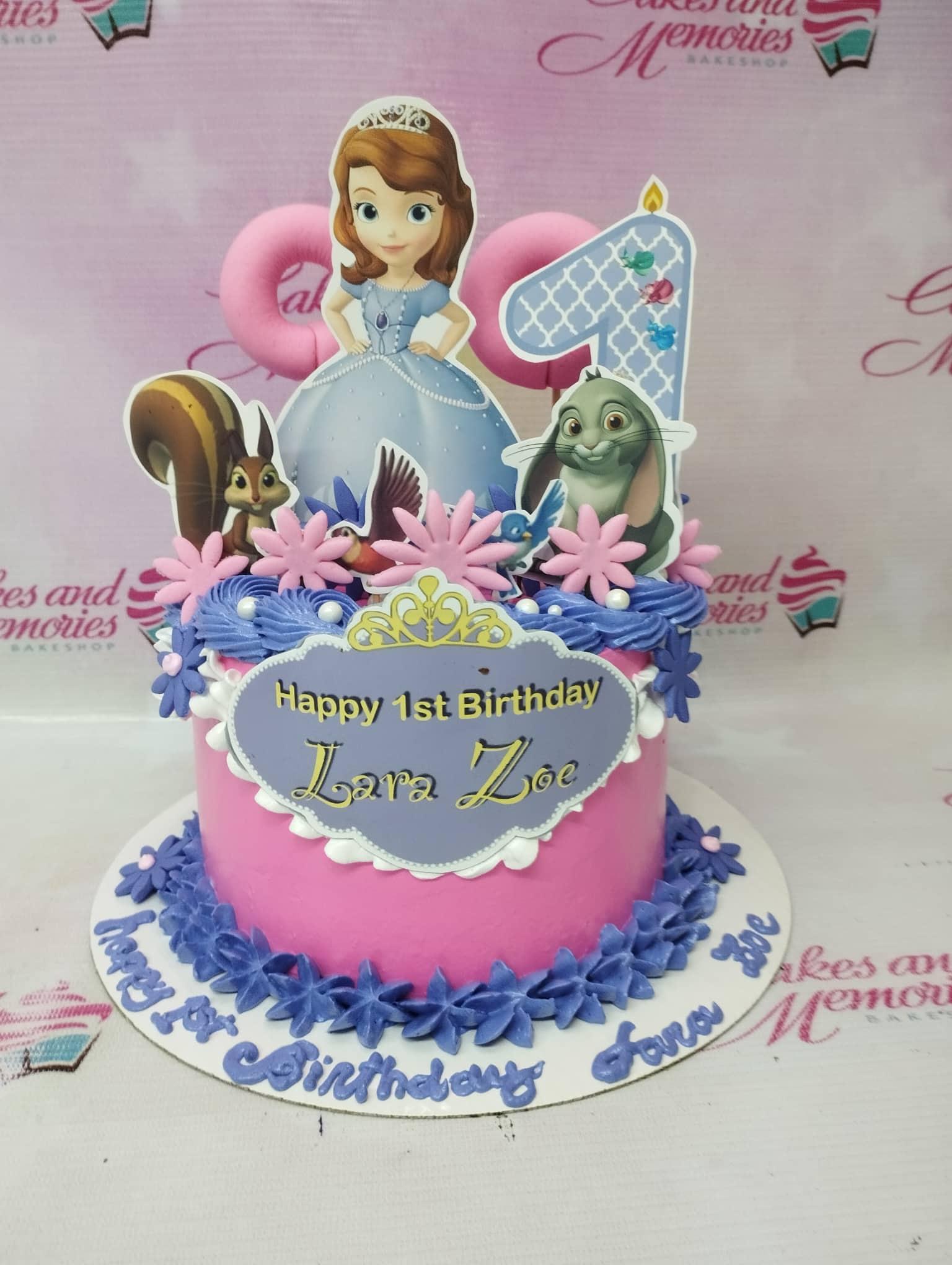 Pink Sofia the First themed birthday cake with purple icing rosettes and character printouts for Lara Zoe's 1st birthday.