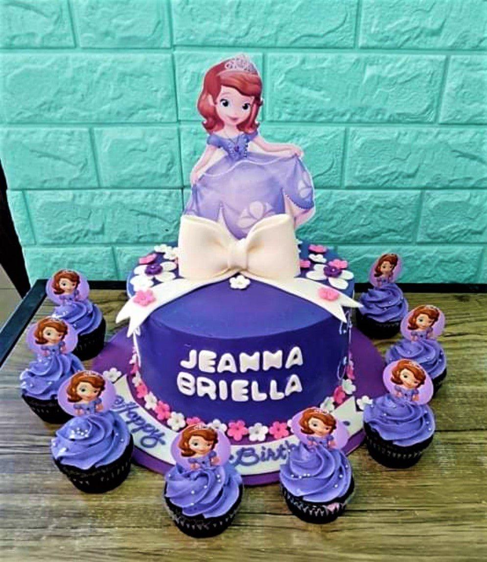 Purple Sofia the First themed birthday cake with a large character topper, white fondant bow, and matching cupcakes.