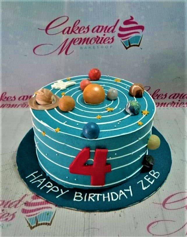 Solar system themed birthday cake with teal icing, white orbital rings, and 3D fondant planets for a 4th birthday celebration.