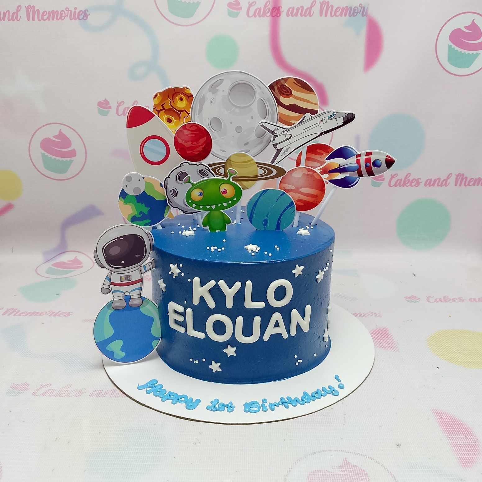 Blue space themed birthday cake with astronaut, planets, rocket, and alien printout toppers for Kylo Elouan's 1st birthday.