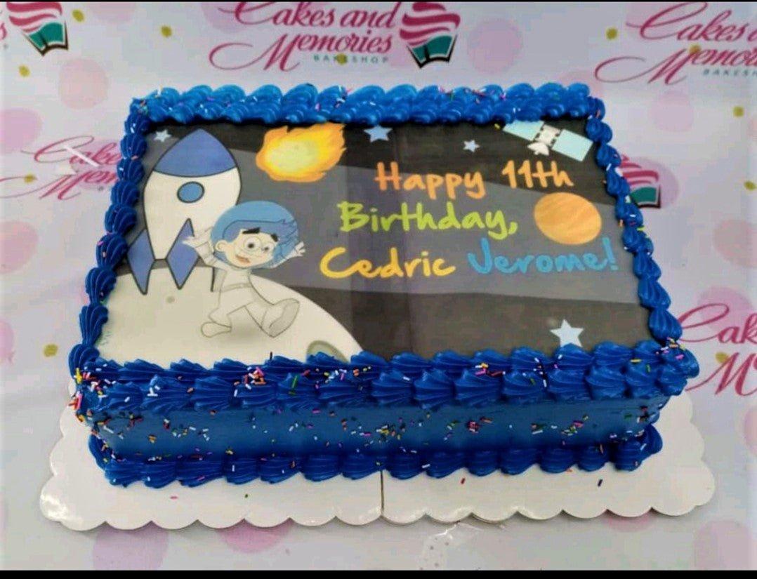 Blue rectangular space themed birthday cake with a large edible photo print of an astronaut and rocket ship.