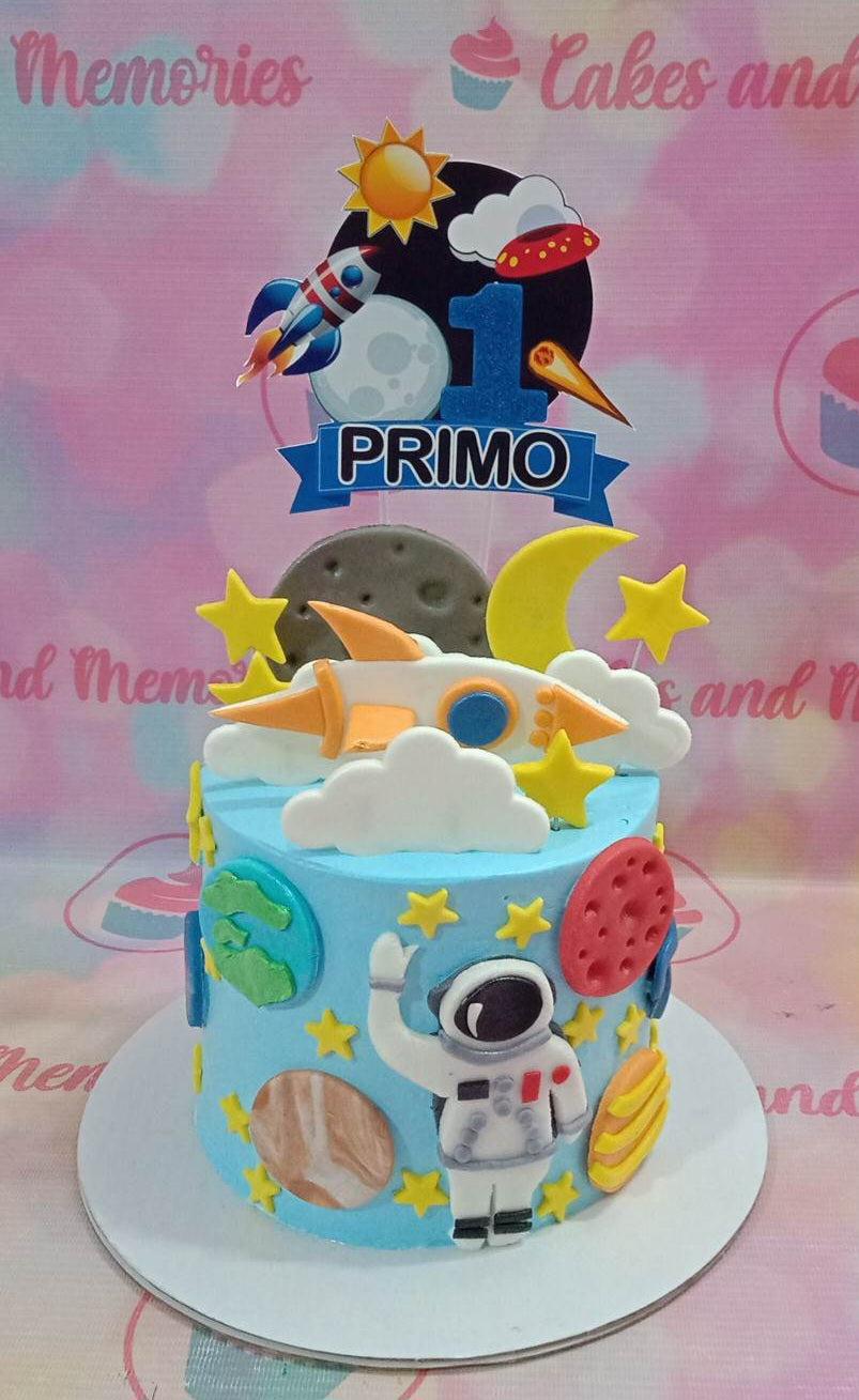 Light blue space themed birthday cake with an astronaut, planets, and a rocket ship topper for Primo's first birthday.
