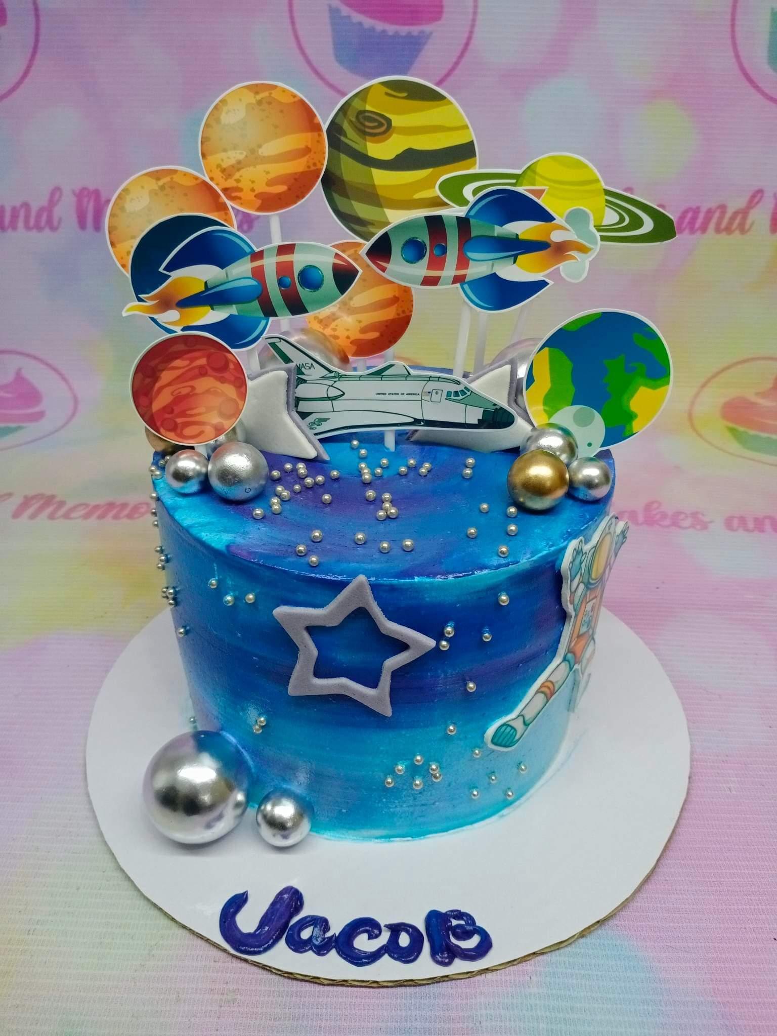Space themed blue galaxy cake with rocket ships, planets, and silver dragees for Jacob's birthday.