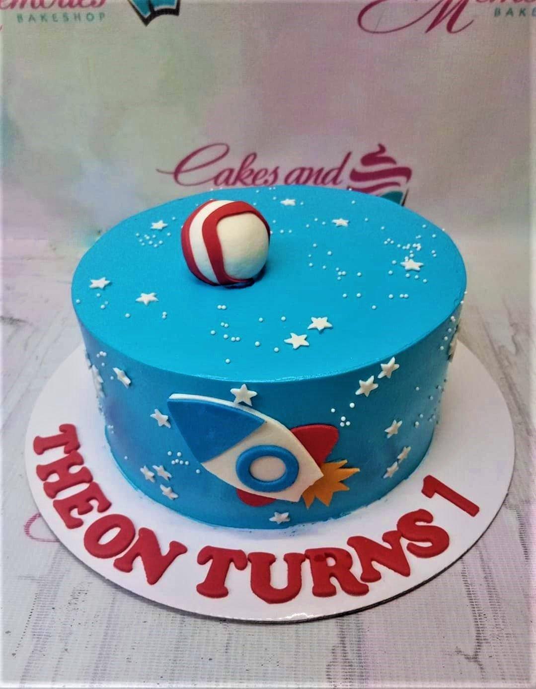 Blue space themed birthday cake with a 3D fondant rocket ship, stars, and a red and white planet topper.