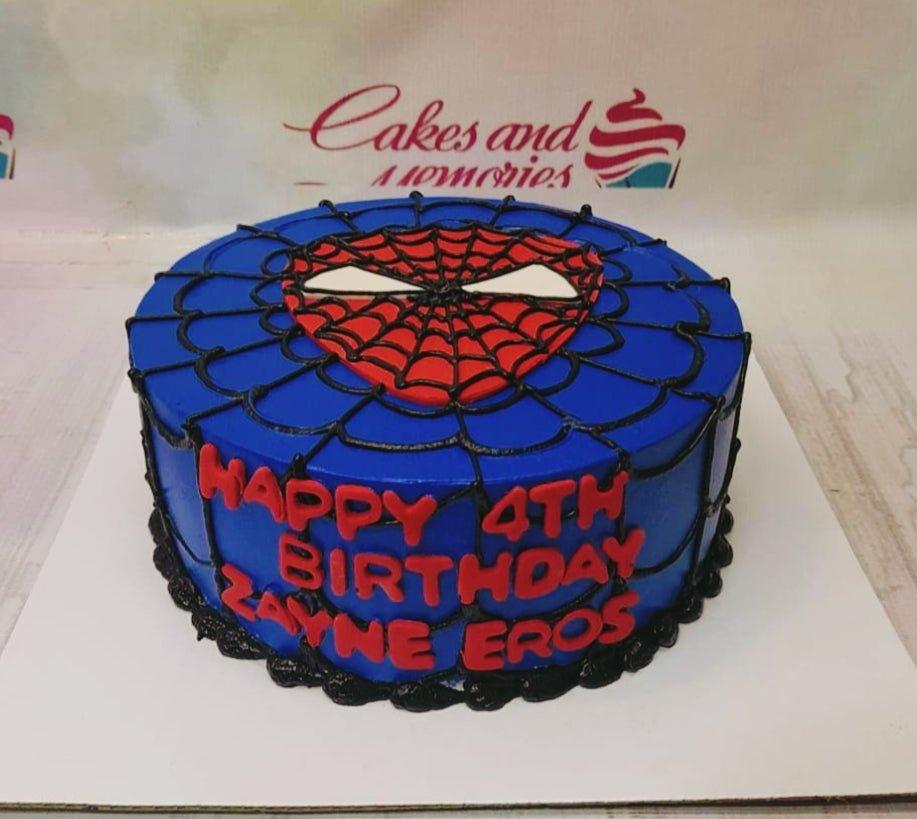 Blue Spiderman themed birthday cake with black web icing and a red Spiderman mask topper.