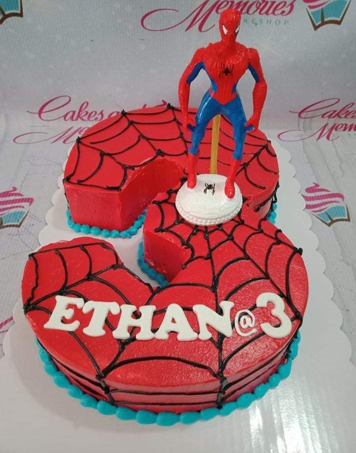 Spiderman themed number 3 shaped cake in red with black web icing and a Spiderman toy topper.