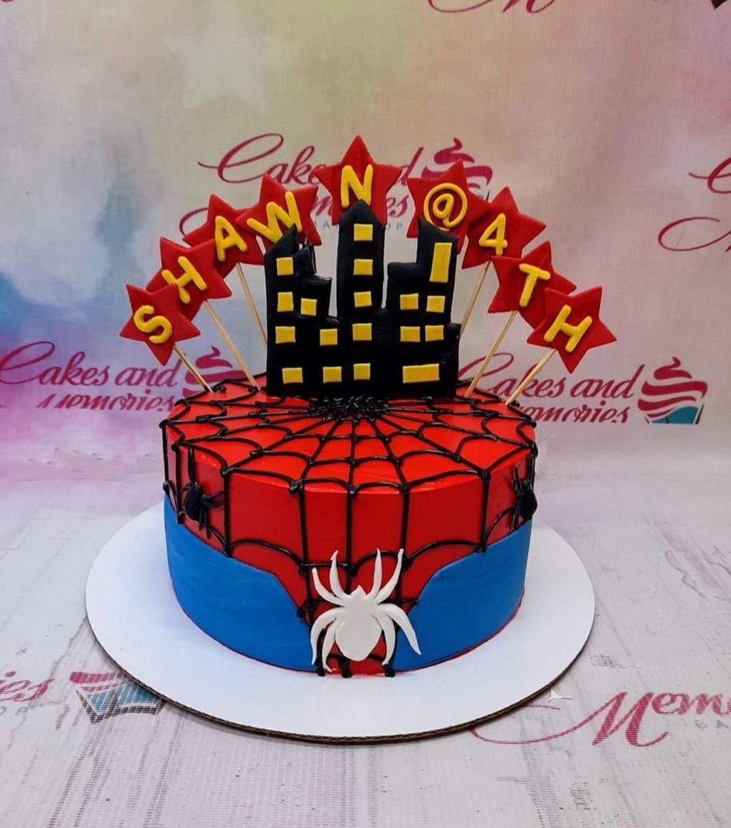 Spiderman themed birthday cake with red and blue icing, black spiderweb piping, and a city skyline topper for Shawn's 4th birthday.