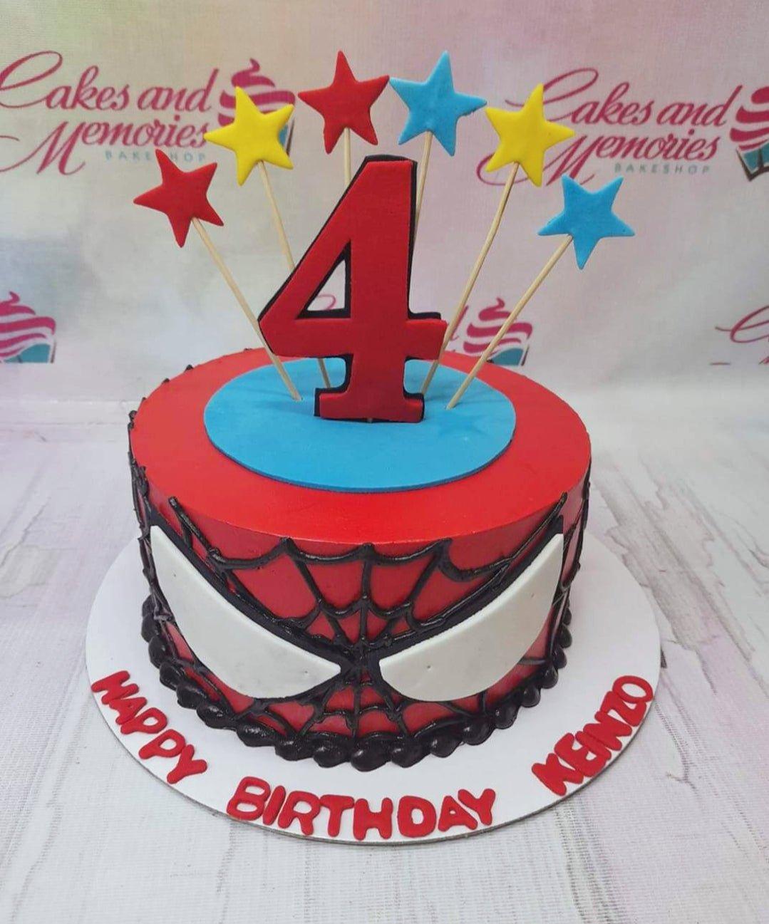 Spiderman themed red birthday cake with black web icing, white eyes, and colorful star toppers for a 4th birthday.