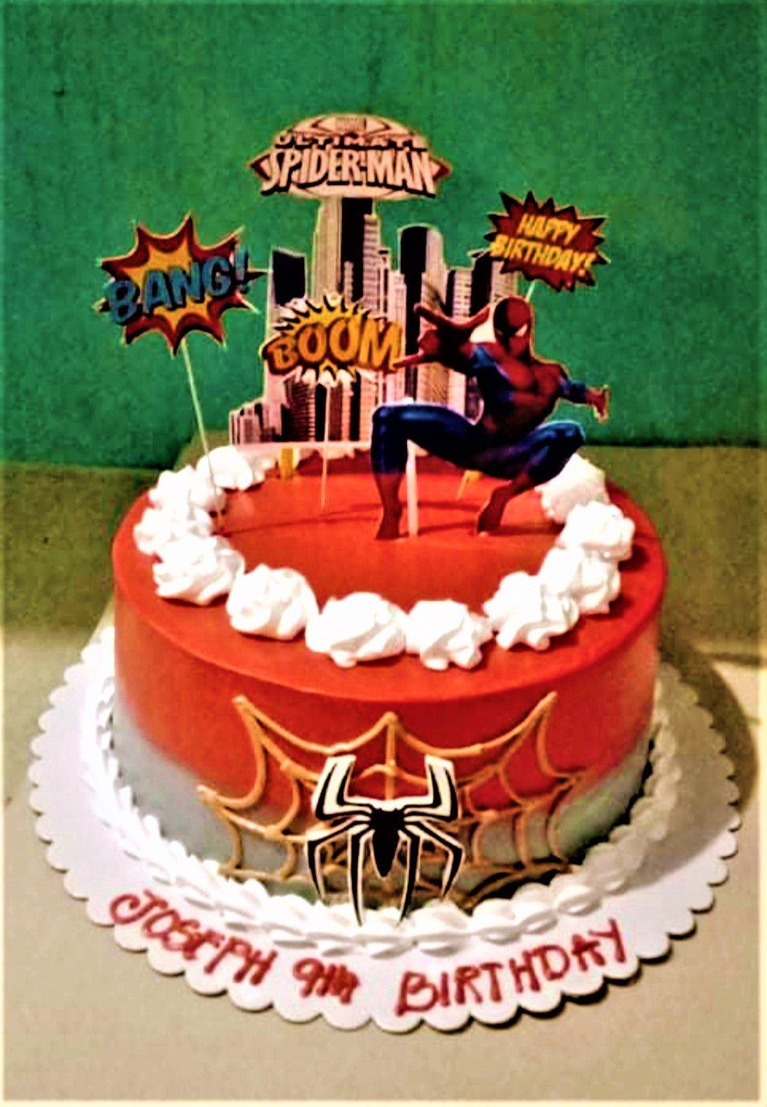 Spiderman themed birthday cake with red and gray icing, spider web design, and various superhero printout toppers.