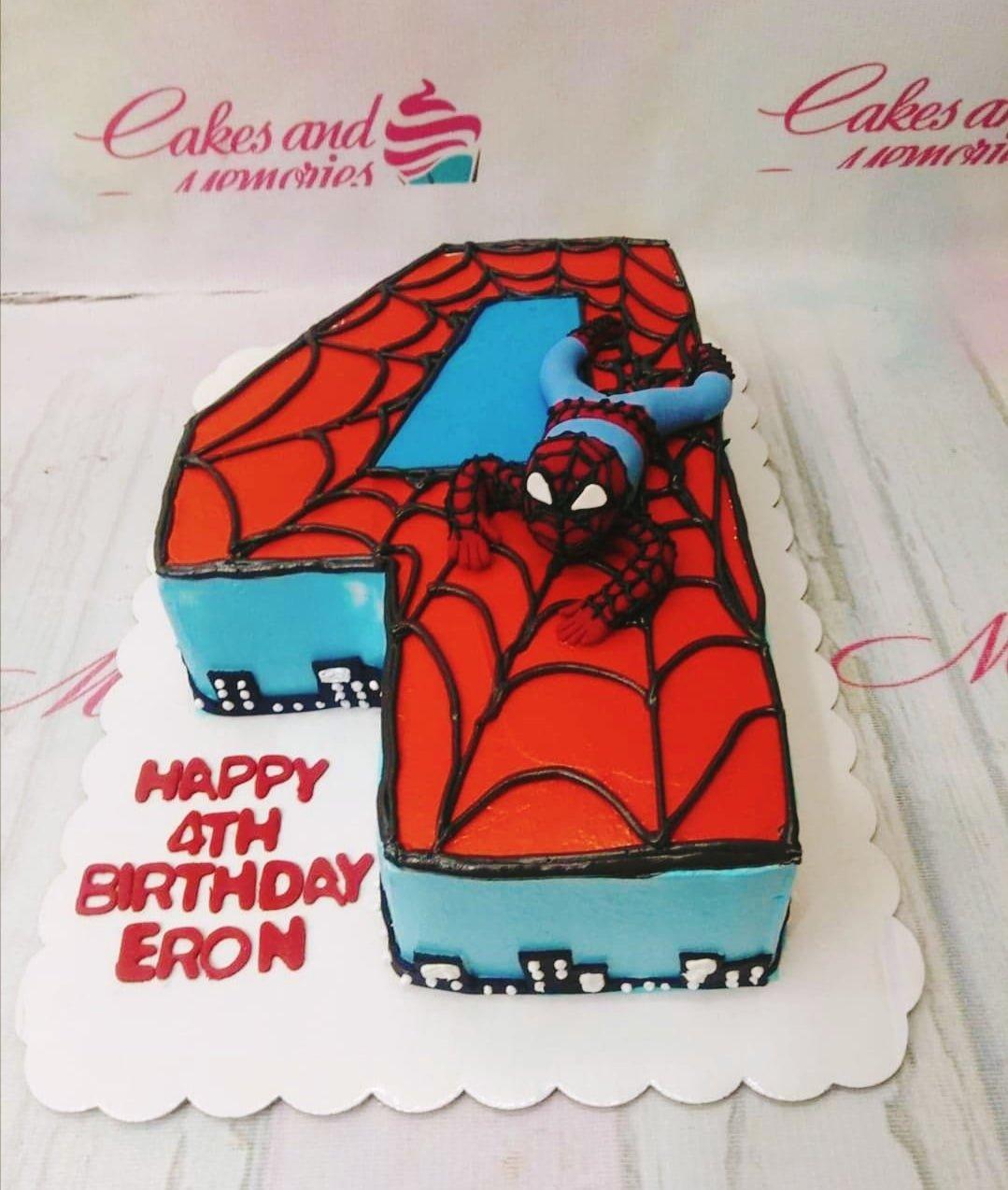 Number 4 shaped Spiderman birthday cake with red and blue icing, black web patterns, and a 3D Spiderman figure.