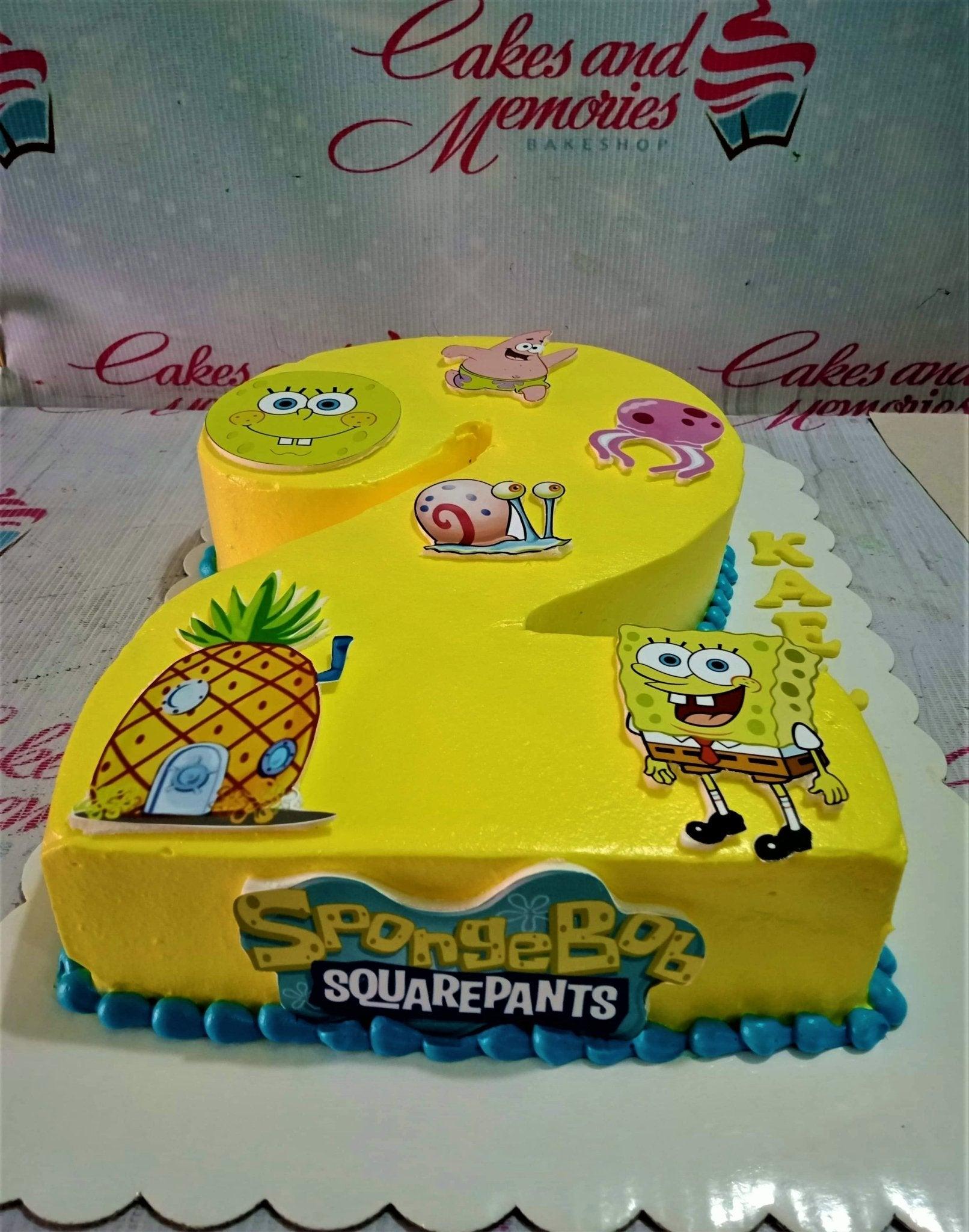 Yellow Spongebob Squarepants number 2 shaped cake with character printouts and blue icing border