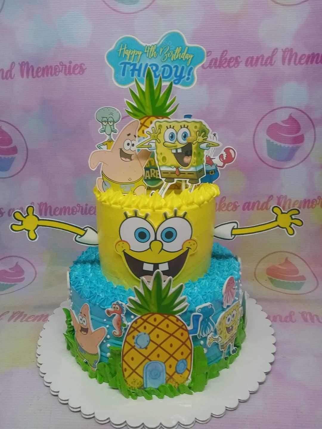 Two-tier Spongebob Squarepants themed birthday cake with yellow and blue icing, character printouts, and a pineapple house topper.