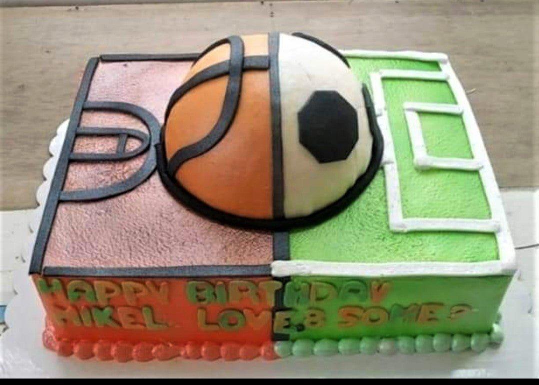 Rectangle sports themed cake split into a basketball court and soccer field with a 3D ball topper and green and orange icing.