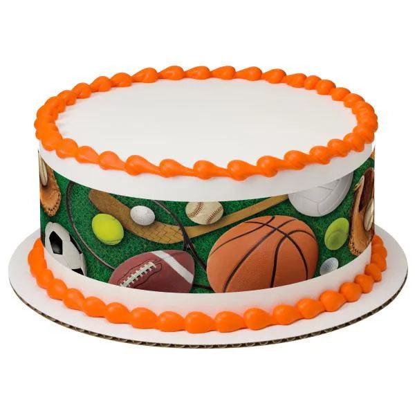 White round sports themed cake with orange icing borders and a side wrap featuring various sports balls like basketball, soccer, and football.