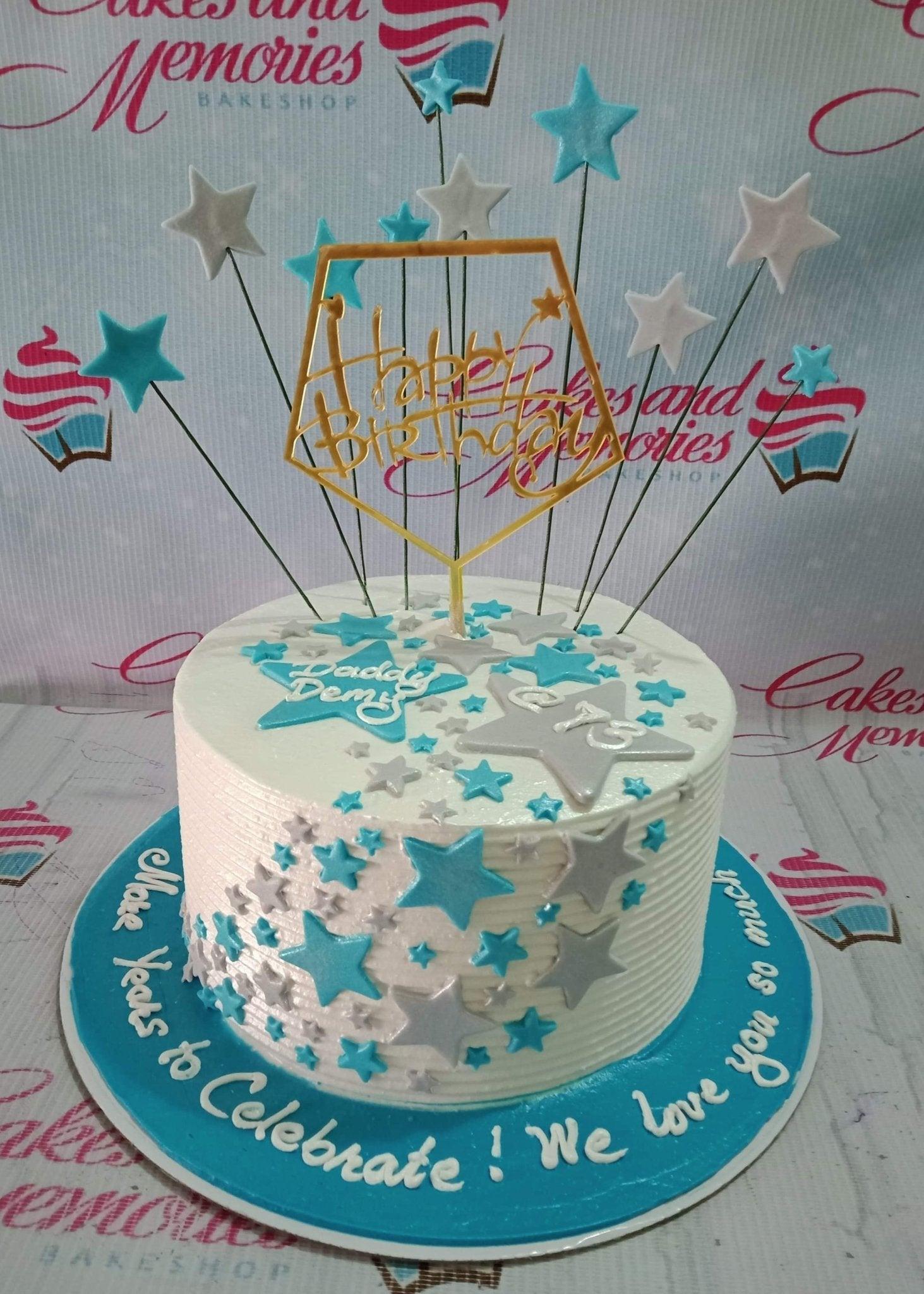 White 1-tier birthday cake with blue and silver fondant stars and a gold Happy Birthday topper