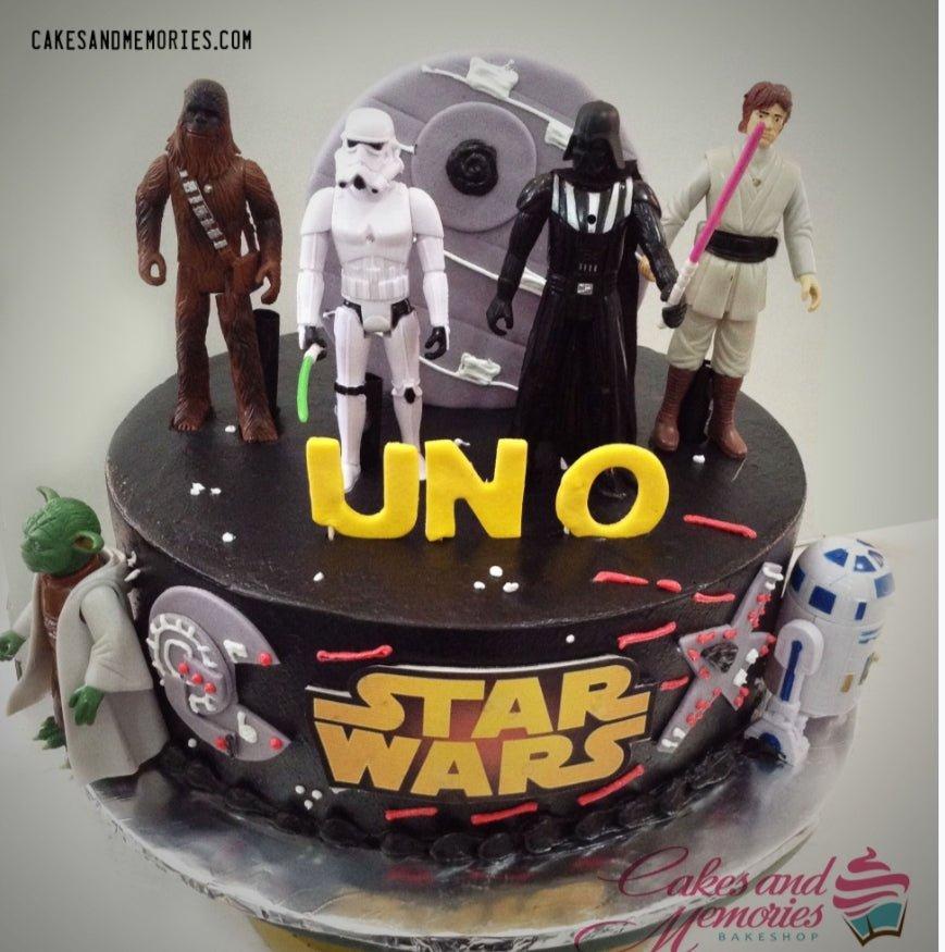 Black Star Wars themed birthday cake with Chewbacca, Stormtrooper, Darth Vader, Luke Skywalker, Yoda, and R2-D2 toy figurines.