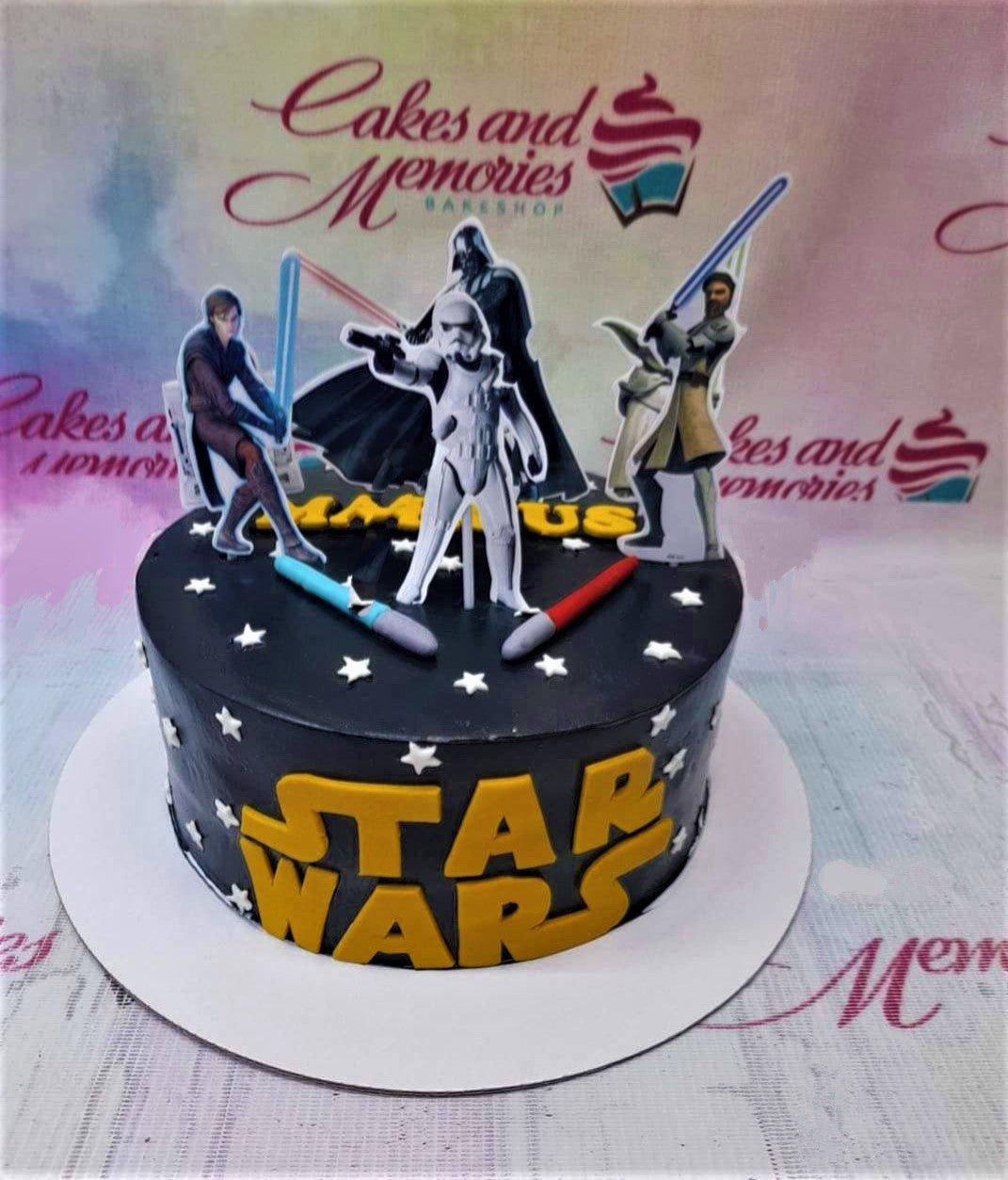 Black Star Wars themed birthday cake with character printouts, lightsabers, and yellow fondant logo.