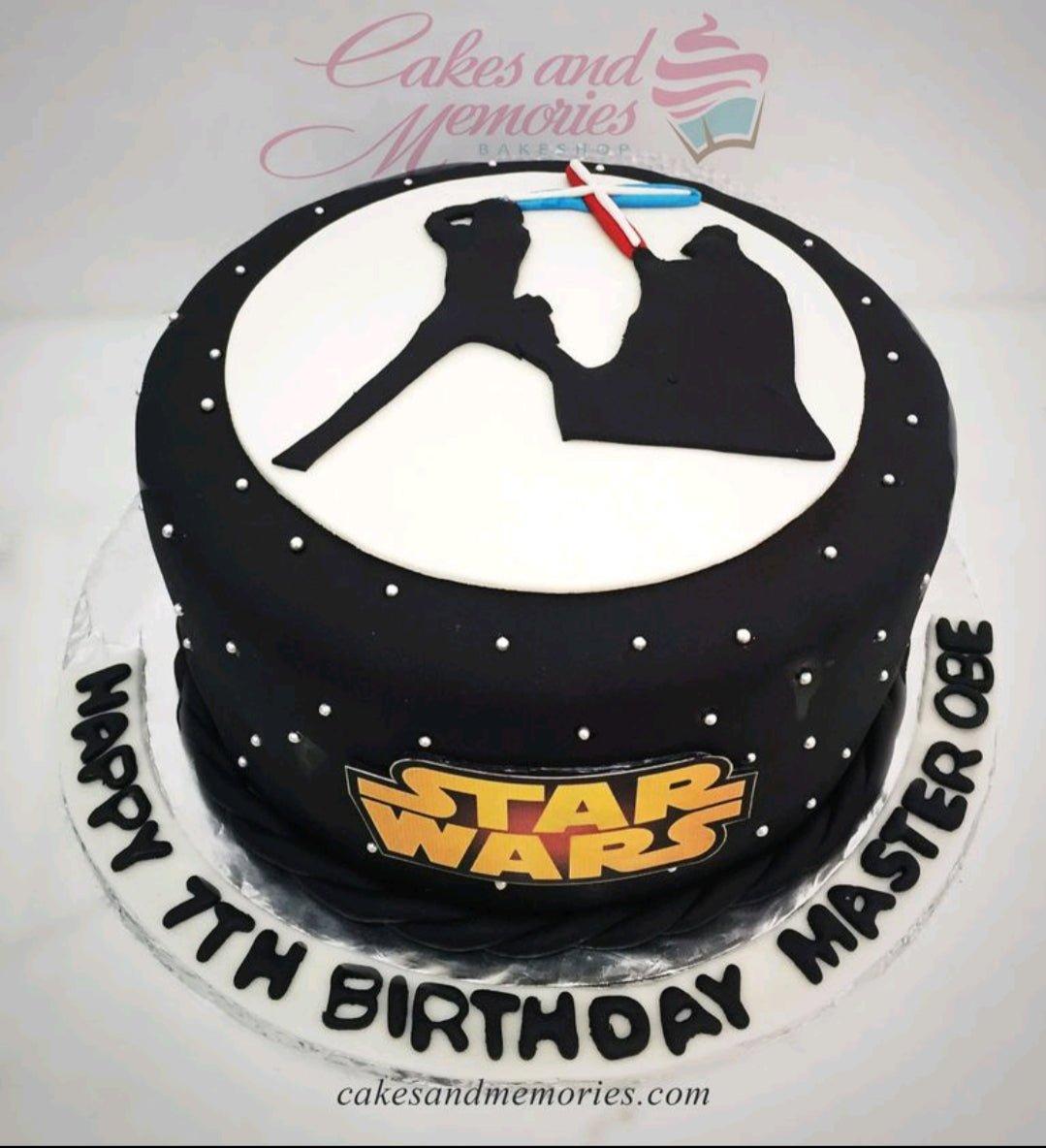 Black Star Wars themed cake with silhouette of Luke Skywalker and Darth Vader battling with lightsabers on a white circular background.