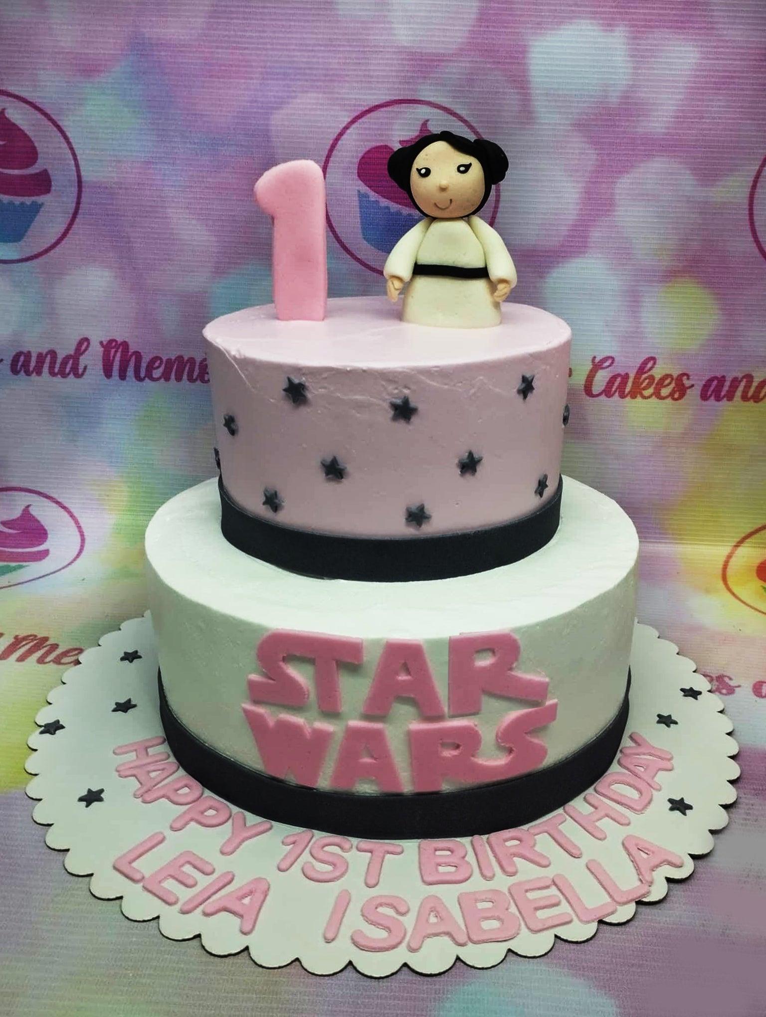 Two-tier Star Wars themed birthday cake with a pink top tier, white bottom tier, and a fondant Princess Leia figure on top.