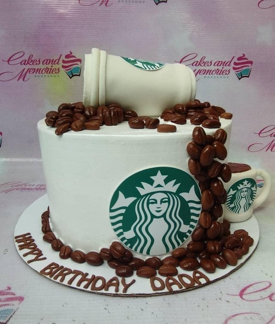 Starbucks themed white cake with a spilled coffee cup topper and edible coffee beans cascading down the side.
