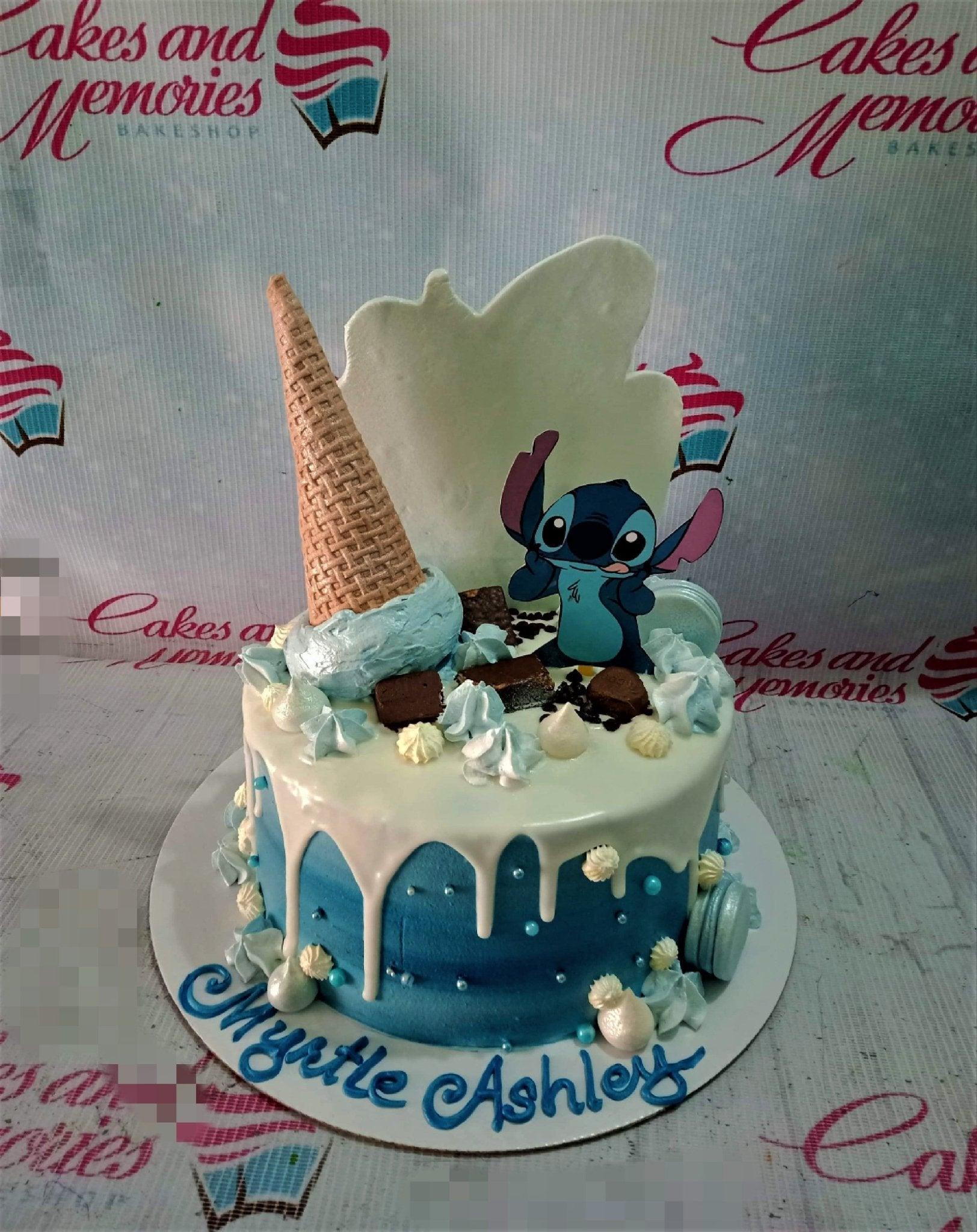 Blue and white drip cake with Stitch character printout, ice cream cone topper, brownies, and macarons.
