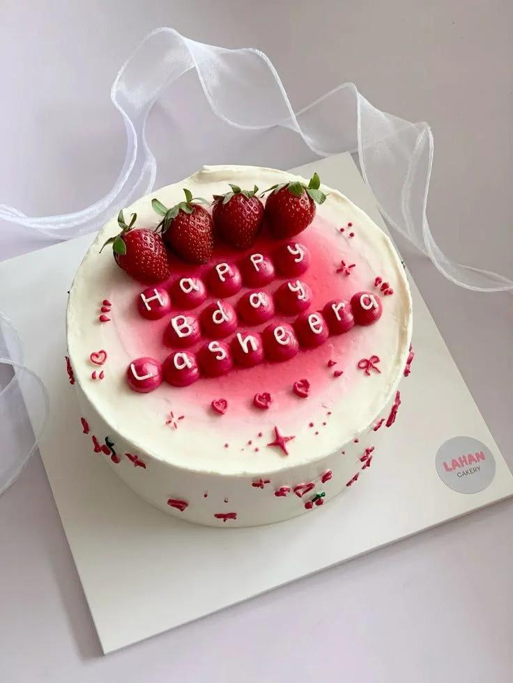 Minimalist white birthday cake with fresh strawberries and pink icing dollops featuring a Happy Birthday message for Lasheera.
